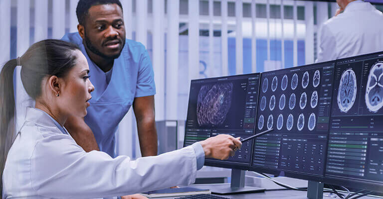 Médico e paciente olhando para o computador onde aparece a imagem de um exame.