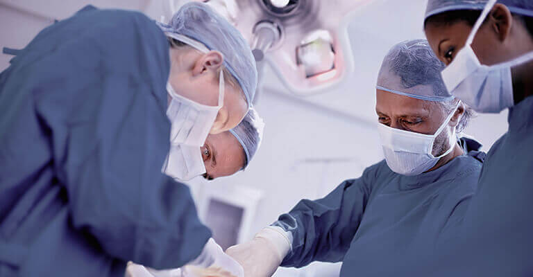 A imagem mostra uma equipe de médico em uma sala cirúrgica. 