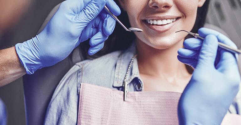 A imagem mostra um profissional odontológico atendendo uma paciente