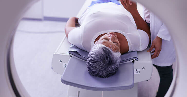 Imagem de uma mulher fazendo uma ressonância magnética.